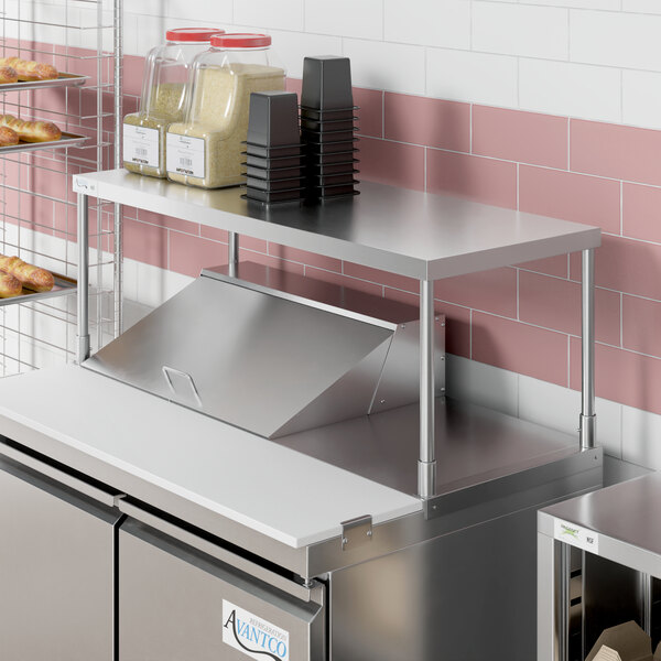 A stainless steel counter with an Avantco stainless steel single deck overshelf on it.