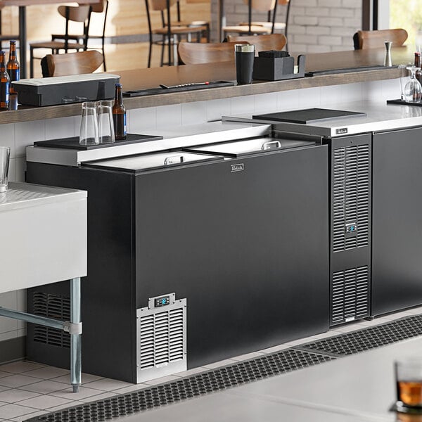 A black Perlick horizontal bottle cooler on a bar counter.