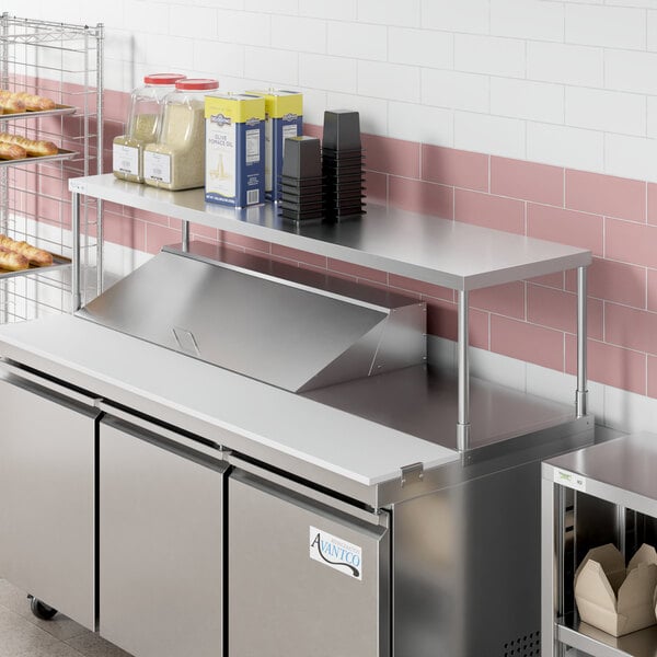 An Avantco stainless steel single deck overshelf on a counter over a refrigerator.