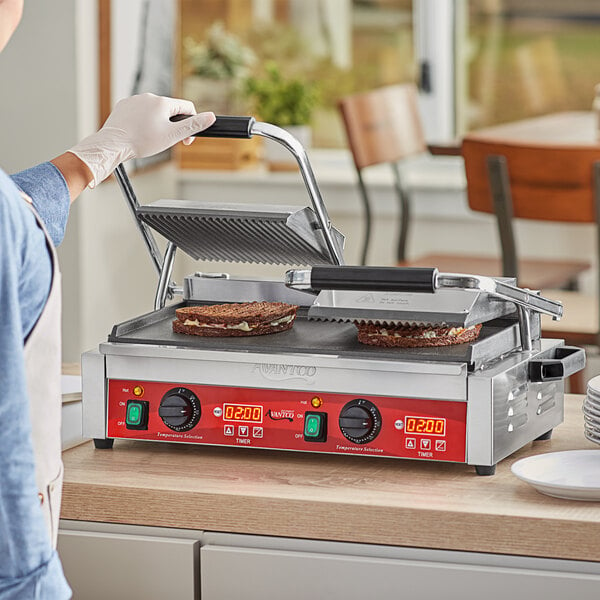 A woman using an Avantco commercial panini grill to make a sandwich.