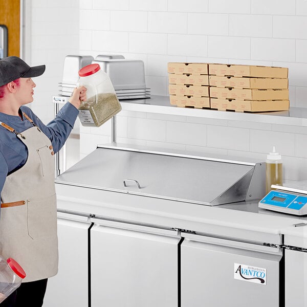 A man wearing an apron using an Avantco stainless steel overshelf over a counter.