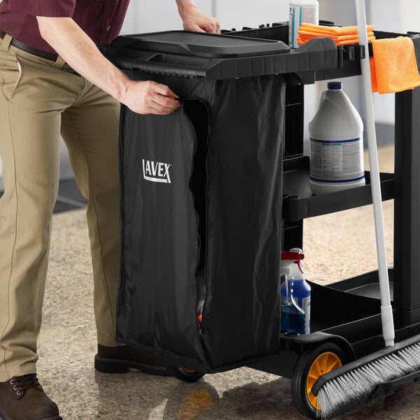 A man putting a black Lavex Premium vinyl bag with a zipper on a cleaning cart.