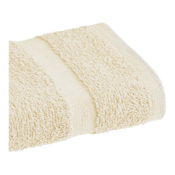 A beige 1888 Mills Fibertone hand towel with a pile of hand towels.
