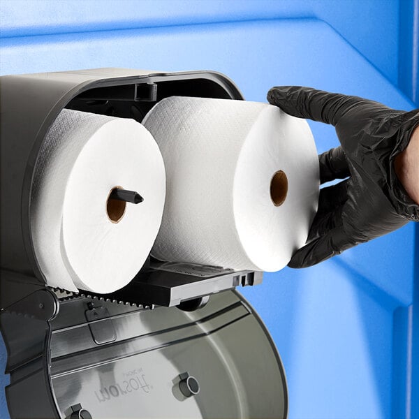 A person in black gloves holding a Morcon Morsoft toilet paper roll