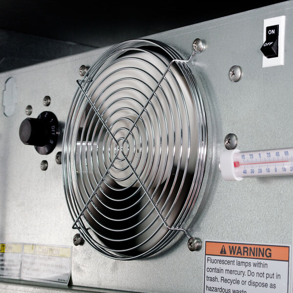 The interior of a Beverage-Air back bar refrigerator with a thermometer and metal fan.