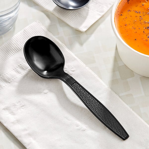 A black Choice plastic soup spoon on a napkin.