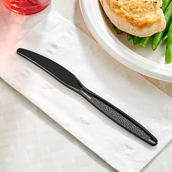 A black Choice heavy weight plastic knife on a napkin.