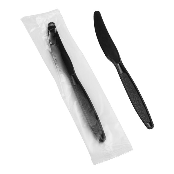 A plastic bag with a black plastic knife with a black handle inside.