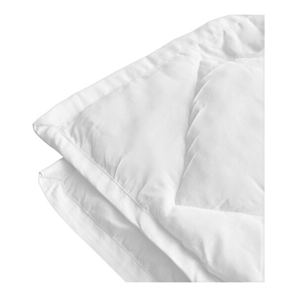 A close-up of a white 1888 Mills Eco Comfort comforter on a white surface.
