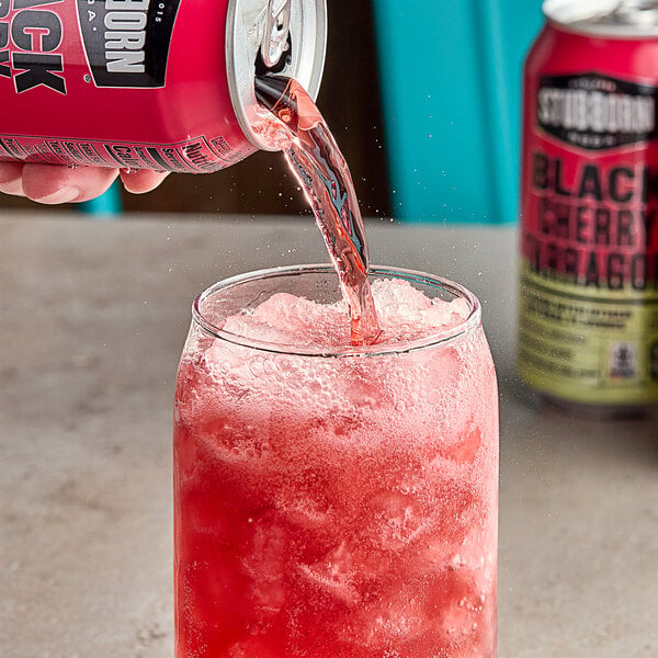 A person pouring Stubborn Black Cherry Tarragon Soda into a glass.