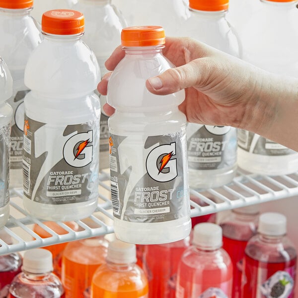 A person holding a close-up of a red Gatorade Frost Glacier Cherry sports drink bottle.