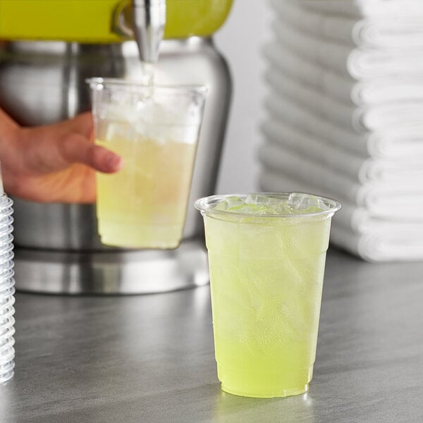 A person pouring Gatorade Thirst Quencher Lemon Lime sports drink powder into a cup of yellow liquid.