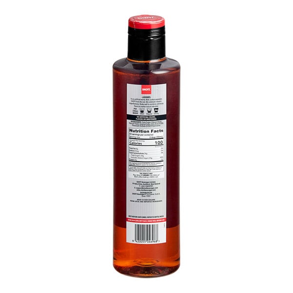 A close-up of a SHOTT Caramel Flavoring Syrup bottle with a red cap.