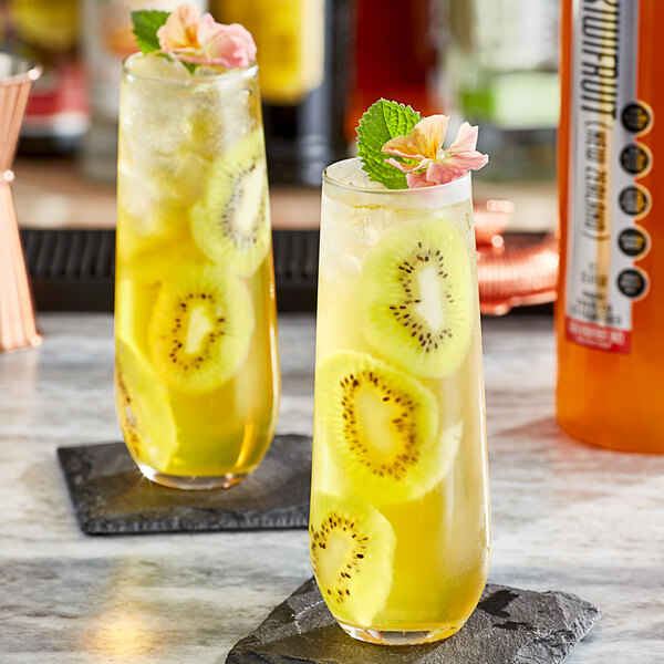 Two glasses of SHOTT Gold Kiwifruit syrup and lemonade with fruit slices on top.