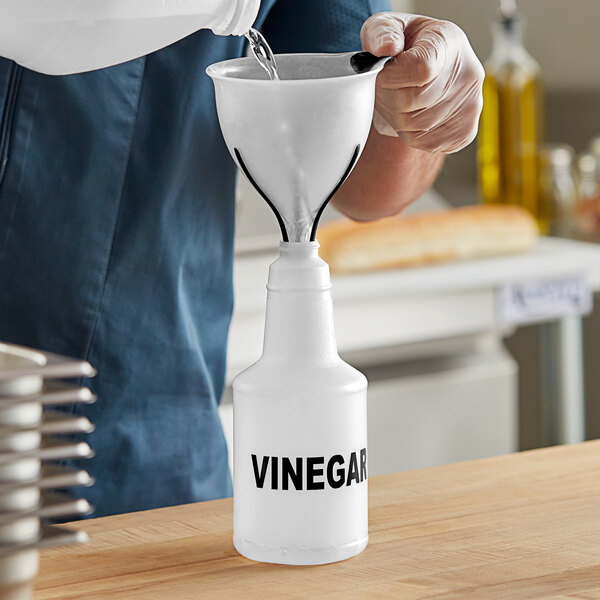 A man pouring vinegar into a white Labeled Bottle.