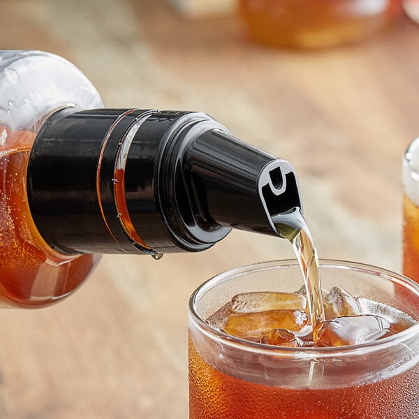 A SHOTT pour top on a bottle pouring liquid into a glass with ice.