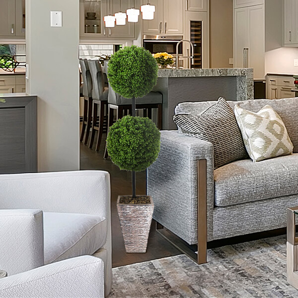 A LCG Sales artificial double ball boxwood topiary in a faux stone pot on a white couch.