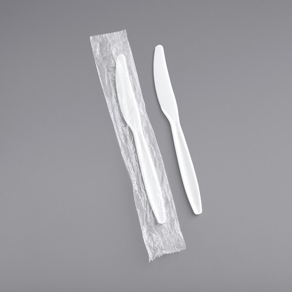 A white heavy weight plastic knife in a plastic wrapper.