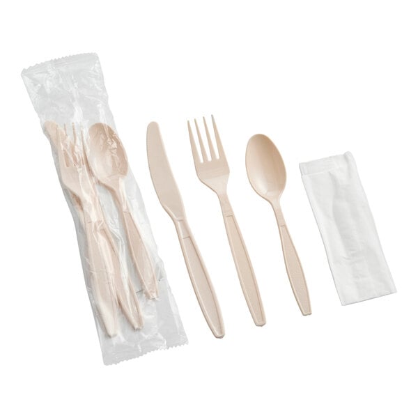 A beige heavy weight plastic cutlery pack with a knife, fork, spoon, and napkin, individually wrapped.