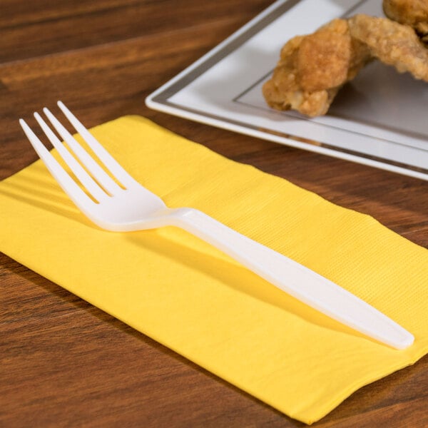 A white plastic fork on a yellow napkin.