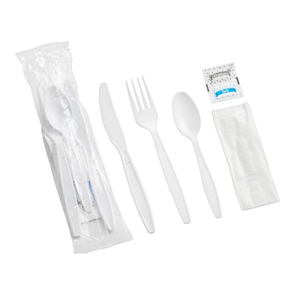 A white heavy weight plastic cutlery pack including a knife, fork, spoon, napkin, and salt and pepper packets.