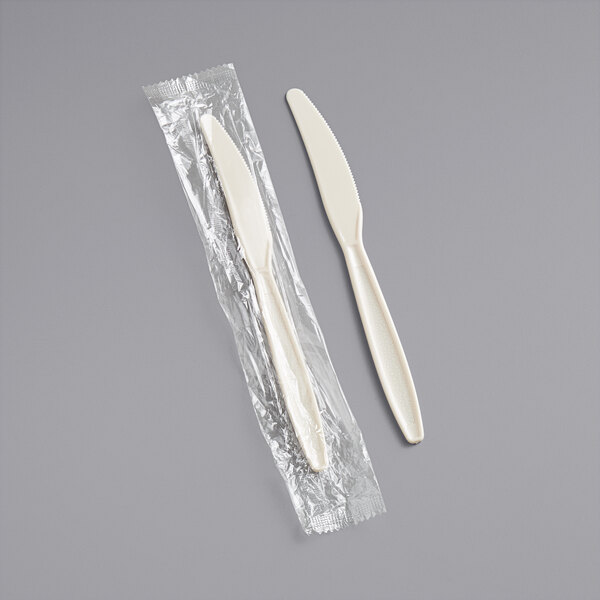 A beige heavy weight plastic knife in plastic wrap.