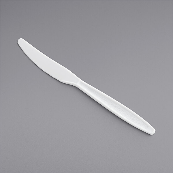 A white plastic knife on a gray surface.