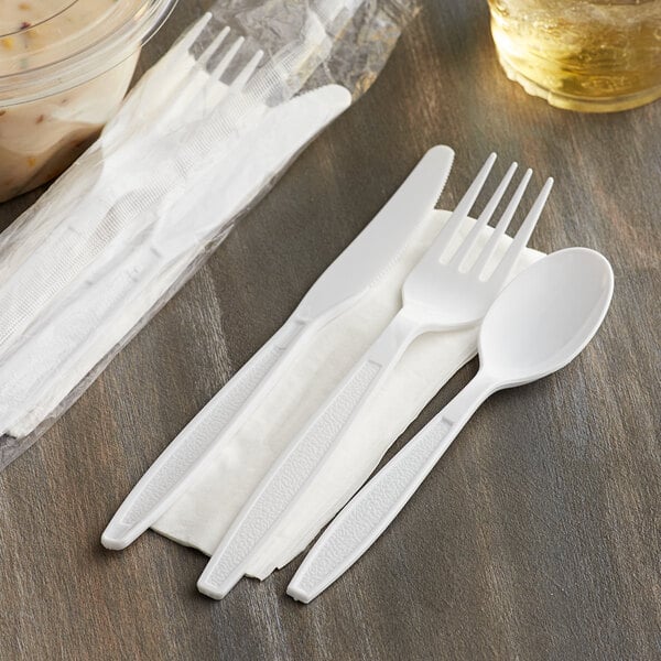 A white plastic wrapped fork and knife on a table.