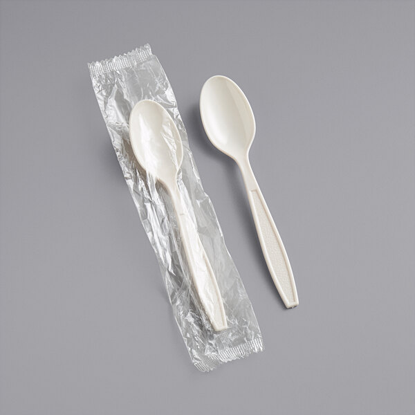 A Choice beige plastic wrapped teaspoon in plastic packaging.