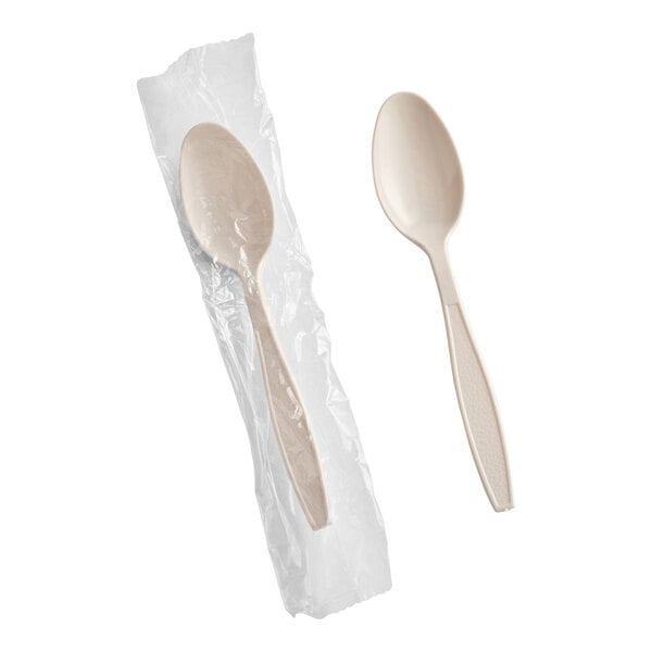 A beige heavy weight polystyrene plastic teaspoon, with one spoon individually wrapped in plastic and one unwrapped.
