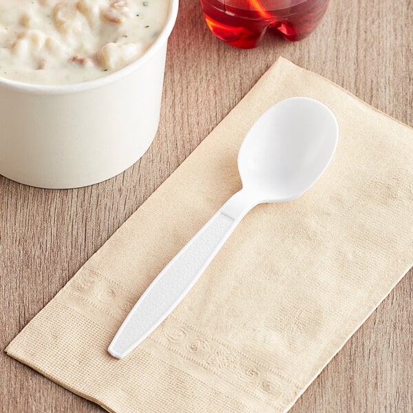 A white plastic soup spoon on a napkin.