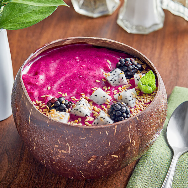 A bowl of pink smoothie with fruit and seeds.