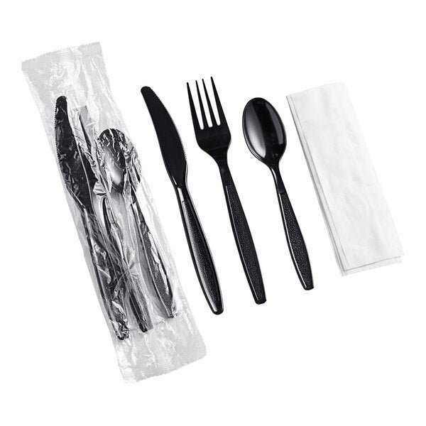 A set of black heavy weight plastic cutlery including a knife, fork, spoon, and a napkin, with the set shown both wrapped and unwrapped.