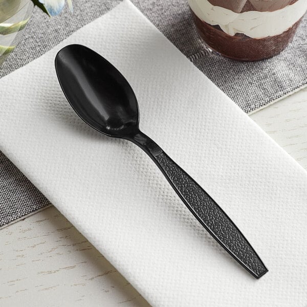 A black Choice plastic teaspoon on a napkin.