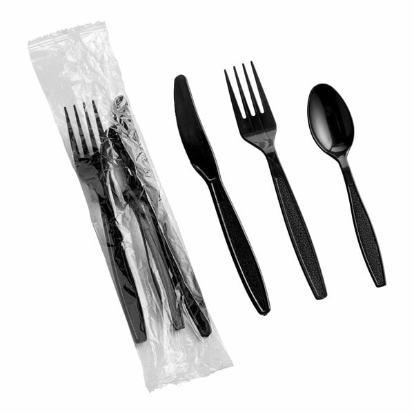 A set of black heavy weight plastic cutlery including a knife, fork, and spoon, with one set wrapped in plastic.