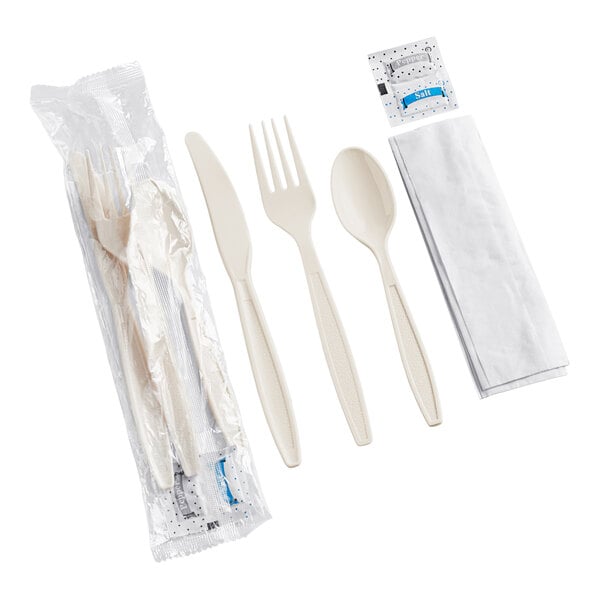 A beige heavy weight plastic cutlery pack containing a knife, fork, spoon, napkin, and salt and pepper packets.