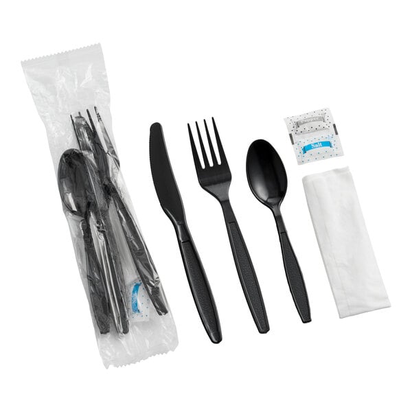 A set of black heavy weight plastic cutlery including a knife, fork, spoon, napkin, and salt and pepper packets, individually wrapped.
