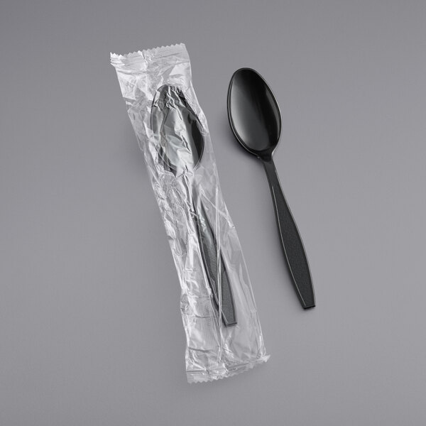 A plastic wrapped black Choice heavy weight teaspoon.