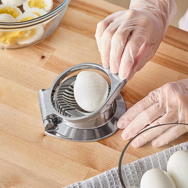 A person using a Choice round aluminum hinged egg slicer to slice a hard boiled egg.