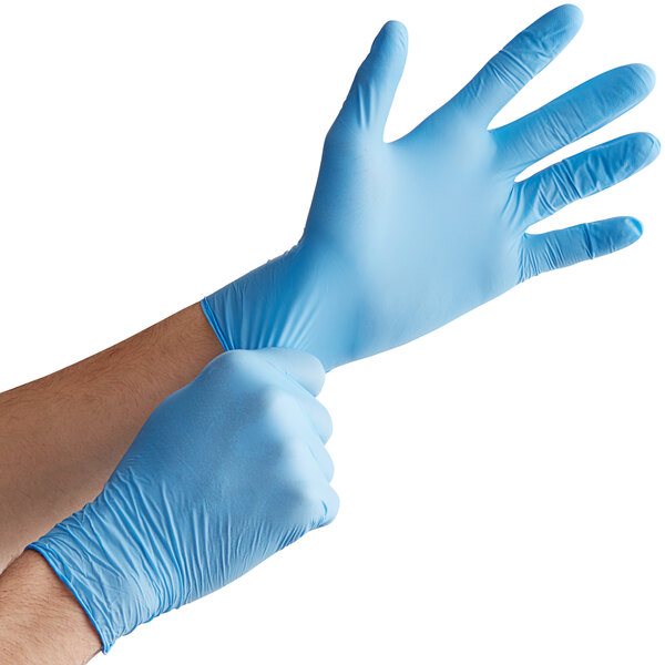 A person wearing blue Noble Products Nitrile gloves.