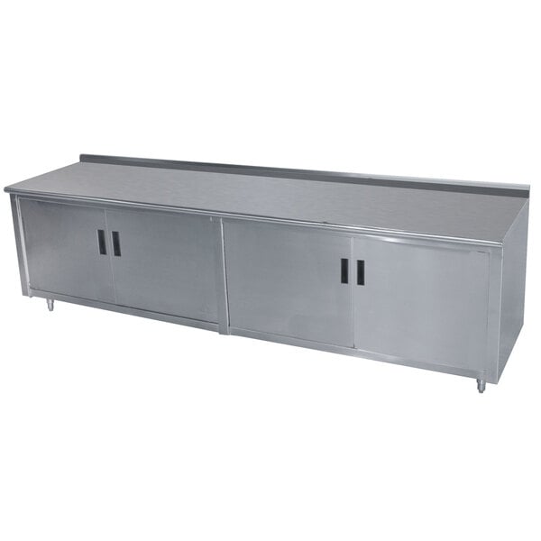 A stainless steel Advance Tabco enclosed base work table with a fixed midshelf.