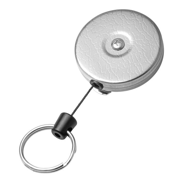 A close-up of a silver metal KEY-BAK keychain with a key on it.