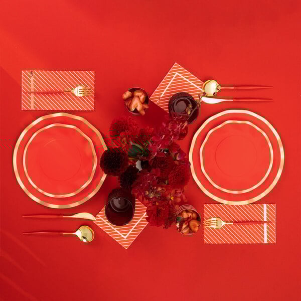 Sophistiplate Bella gold and red plastic cutlery on a table with red and gold place settings.
