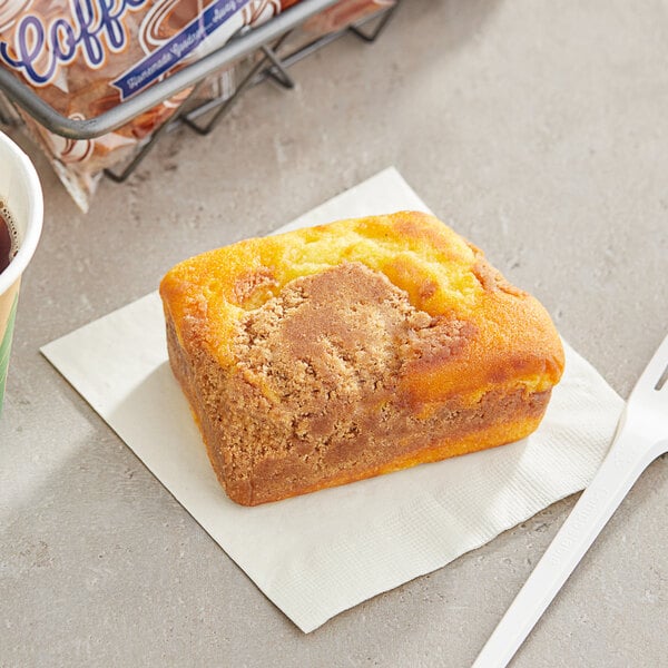 A piece of Ne-Mo's Bakery Streusel Coffee Cake on a napkin next to a cup of coffee.