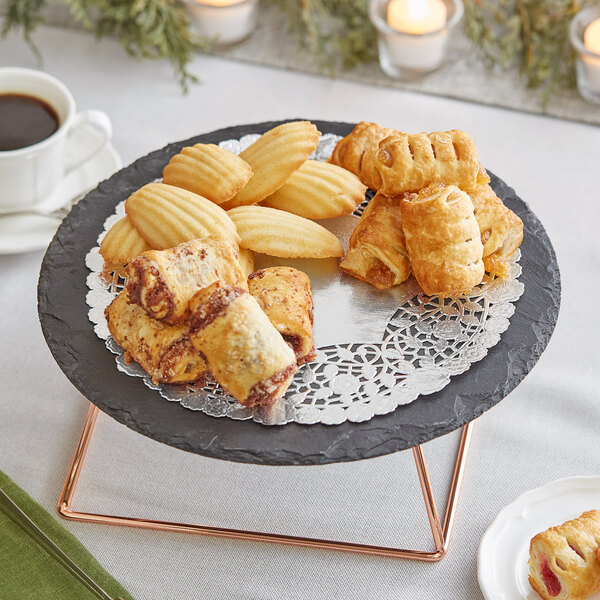 A 10" silver foil lace doily on a plate of pastries and coffee.