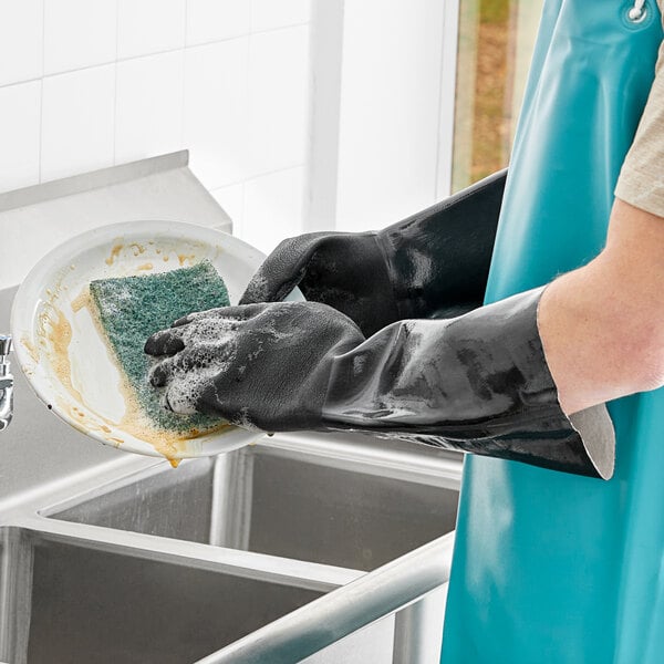 A person wearing San Jamar dishwashing gloves cleaning a dish.