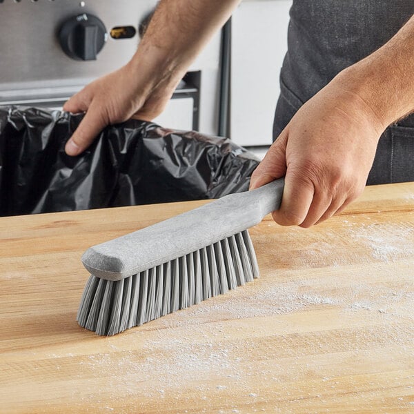 A hand using a Carlisle Sparta soft polyester counter brush to clean a counter.