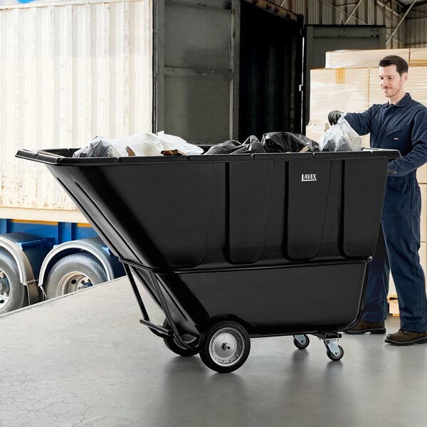 A man in a black shirt and pants standing next to a large black Lavex tilt truck.