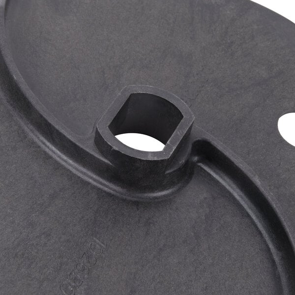 A black plastic Robot Coupe discharge plate with a hexagon hole and a nut.