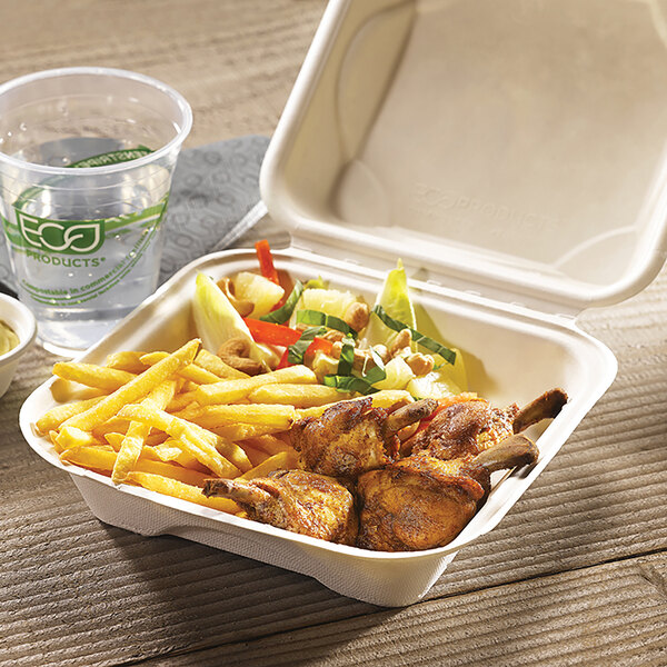 A compostable sugarcane clamshell container filled with fries, grilled chicken, and salad, with a cup of water nearby.
